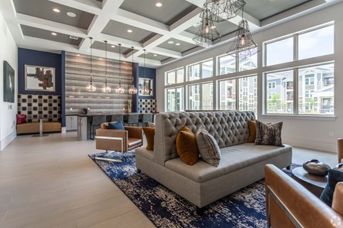 a living room with a couch and chairs and large windows